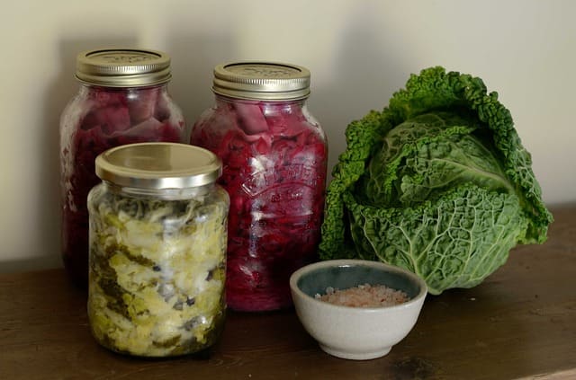 Sauerkraut in glass containers and a whole savoy cabbage
