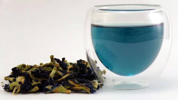 A glass of blue tea and dried blue butterly pea flowers